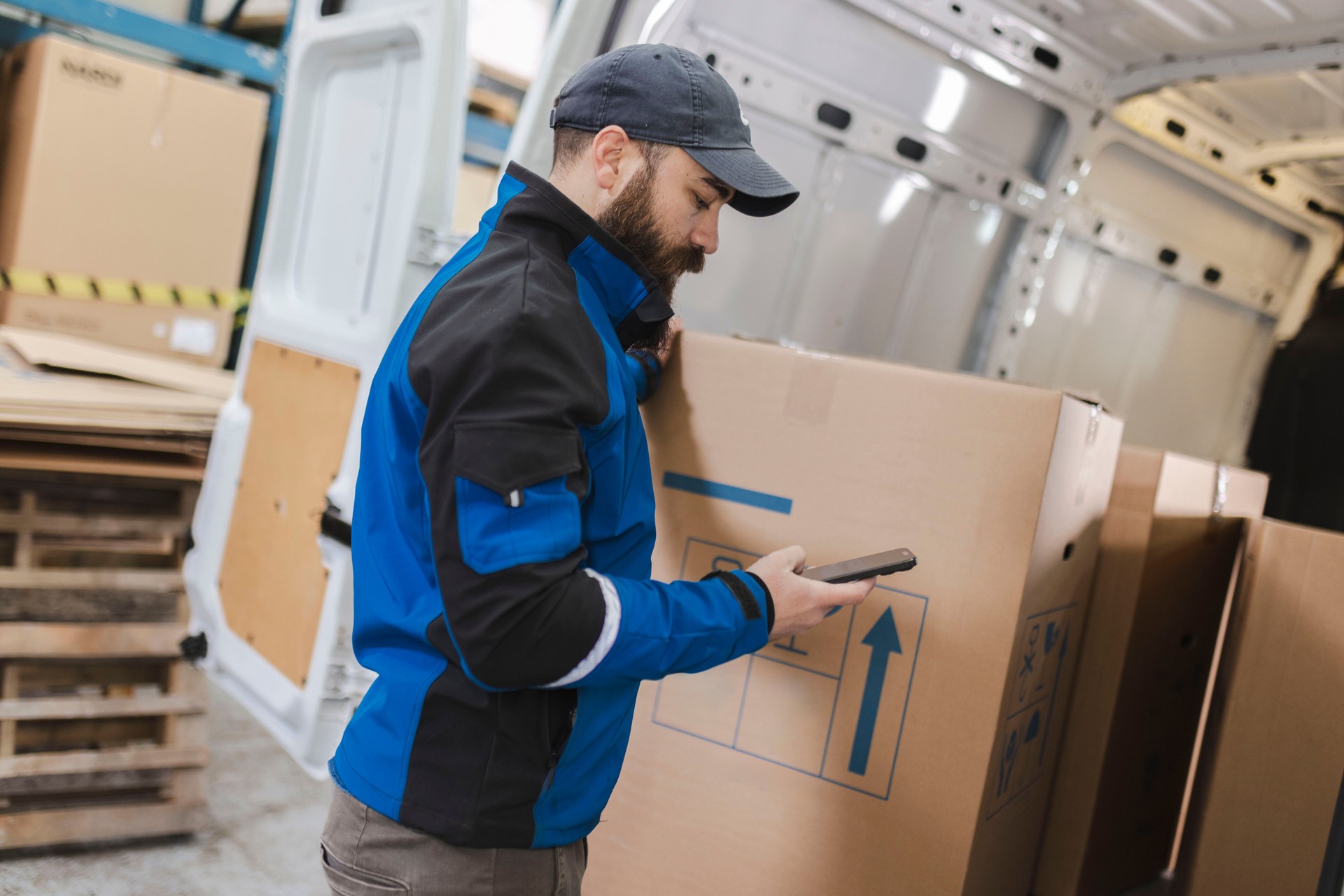 The delivery man uses a mobile phone while preparing the package for delivery to the customer